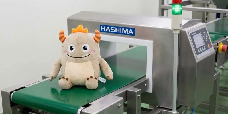 Licensed character plush passing through a conveyor belt metal detector for safety QC