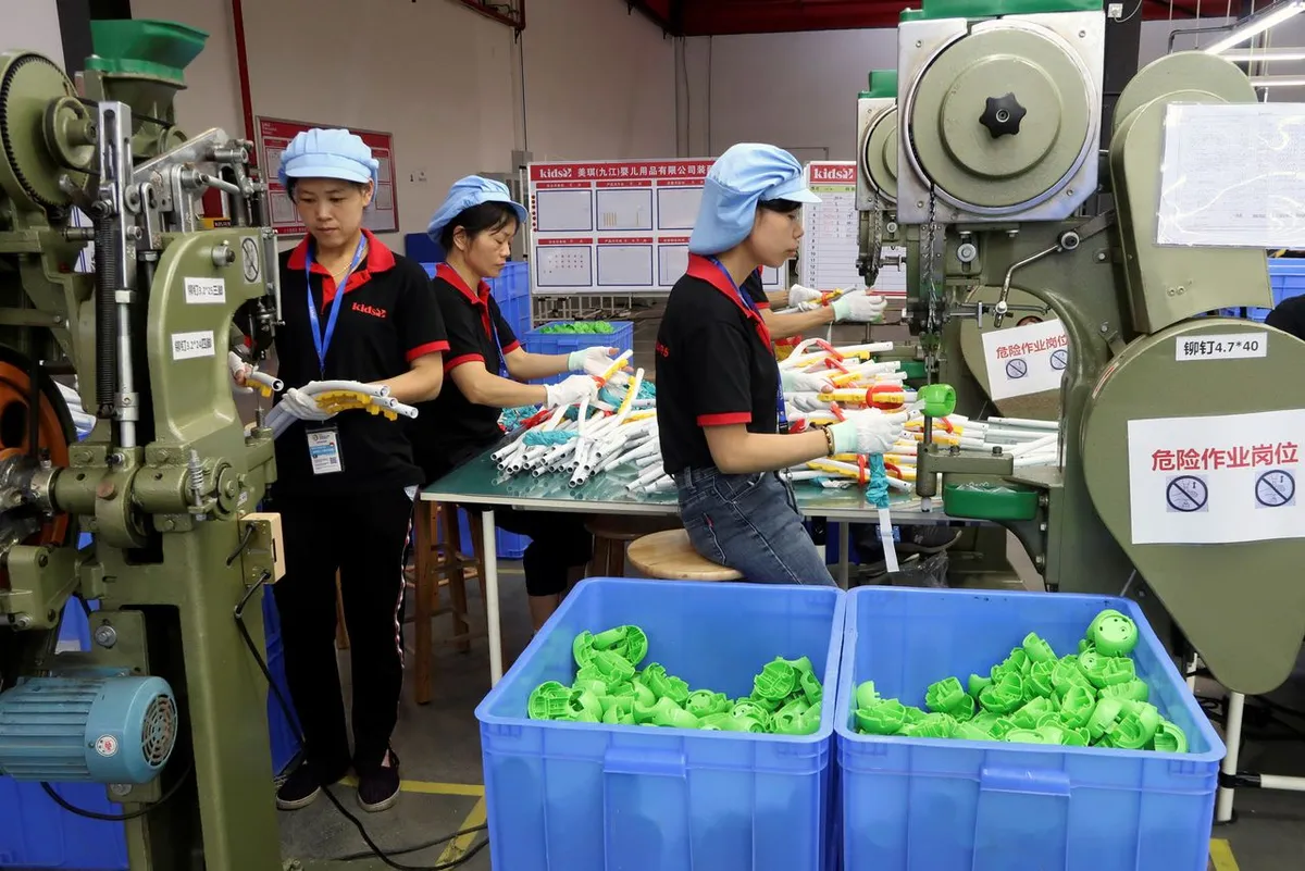 Workers at machinery in a production workshop, with crates of parts alongside