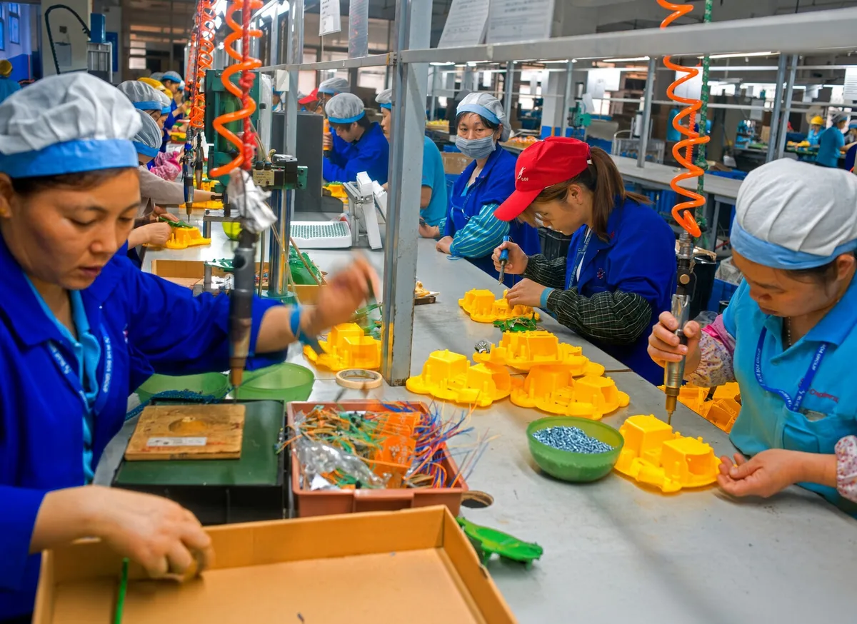 Workers on an assembly line fitting small colourful parts into toys